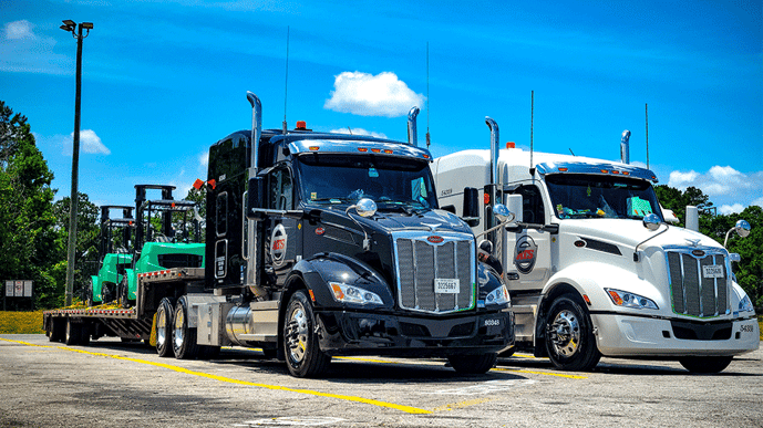 Two ATS-branded semi-trucks in a parking lot.